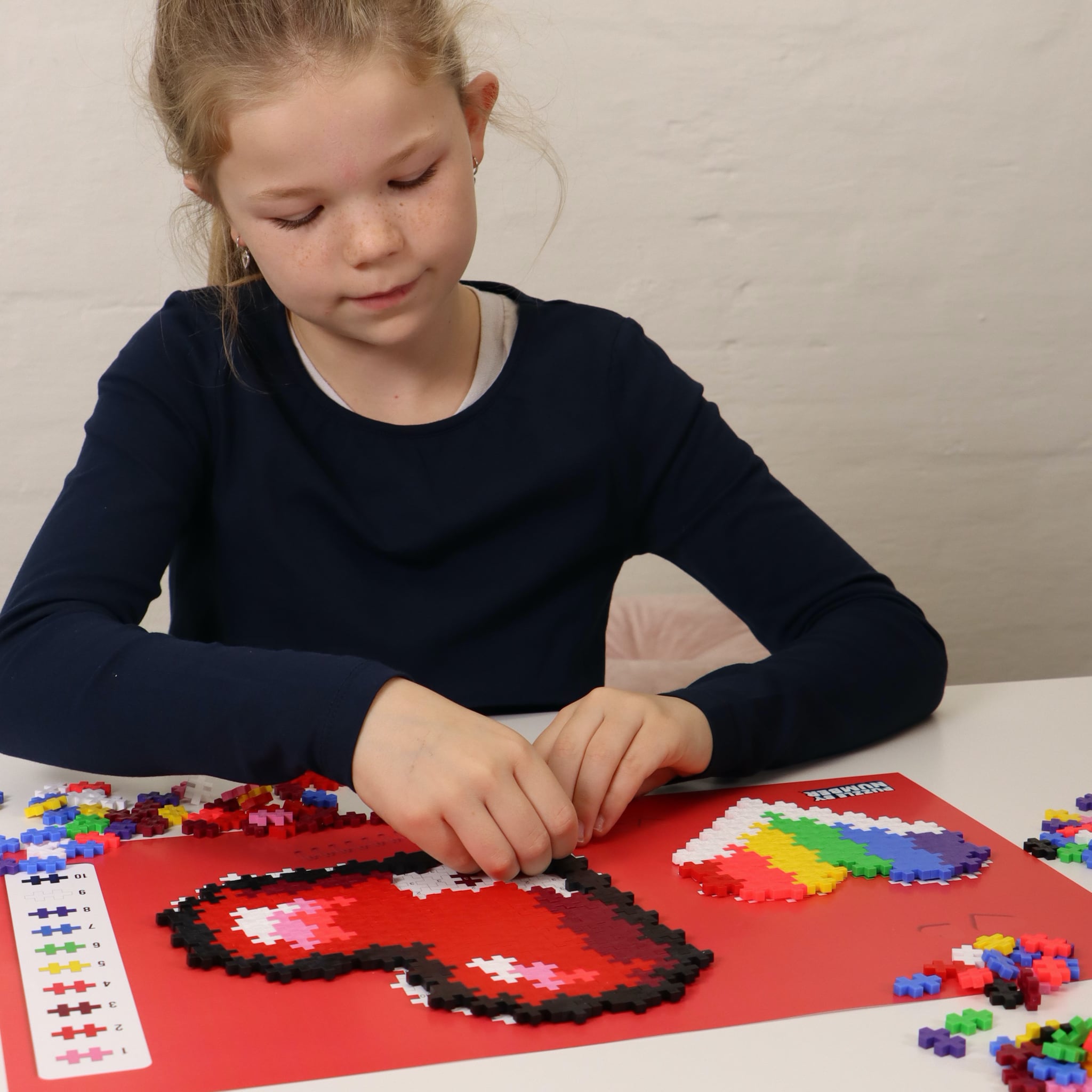 dziewczynka układa serca z klocków plus plus puzzle